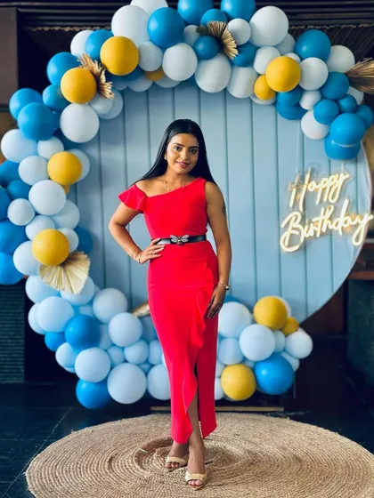The birthday girl looking radiant in front of her custom balloon arch.