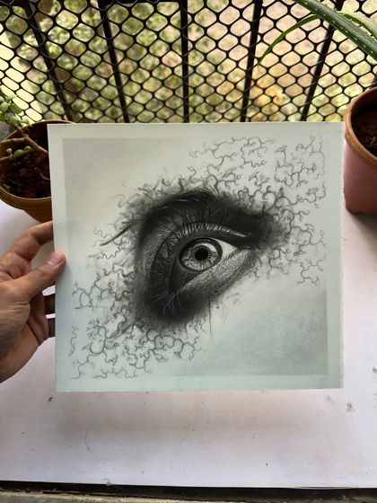 Another angle of the abstract eye drawing, held up outdoors. The natural light highlights the subtle shading and detailed linework.