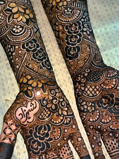 A close-up of a bridal design featuring the groom's name, 'Shehzad', on the palm.