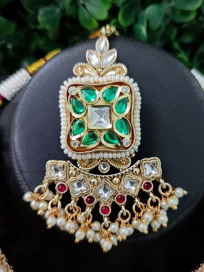 A close-up of the central pendant of the necklace, showing the detailed kundan work.