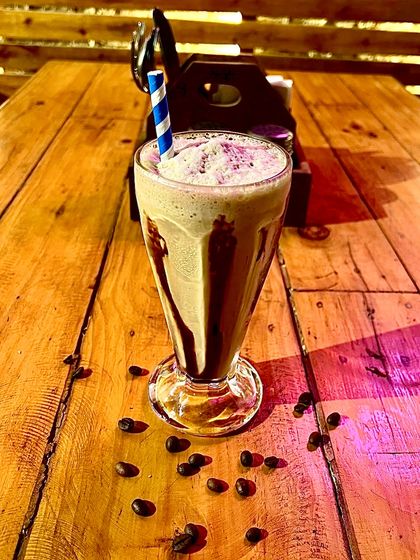 A tall glass of our refreshing cold coffee, drizzled with chocolate sauce.