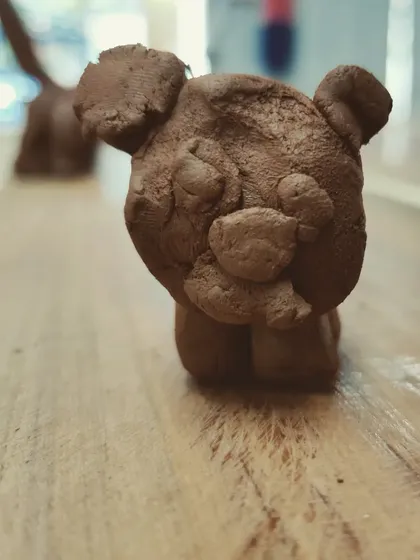 A close-up of a small clay bear, showcasing the simple yet expressive forms that kids can create.