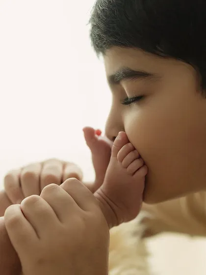The beginning of a lifelong bond. A brother's gentle kiss on his new sibling's tiny foot is a story of love that needs no words. Capturing these first chapters is a true blessing.