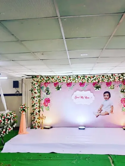 We designed this serene and elegant floral stage for a beautiful naming ceremony. The setup includes a custom backdrop with a photo of the baby, a stunning floral moon-shaped cradle for the ceremony, and soft lighting to create a warm and welcoming atmosphere.