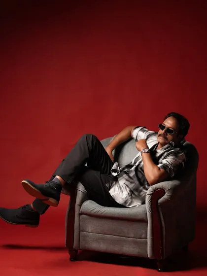 A cool, relaxed shot of an actor for a fashion editorial with Sol by LOC. The grooming was minimal and modern, focusing on a clean finish to complement the stylish outfit and red backdrop.