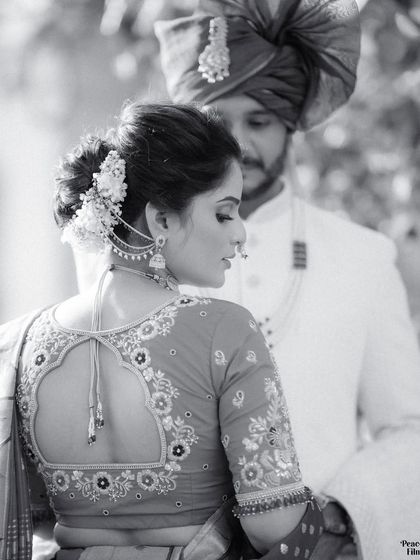 An artistic black and white portrait focusing on the intricate design of the bride's blouse and her traditional hairstyle.