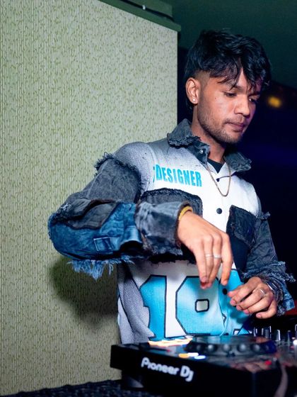 A focused shot of me in a designer jacket, mixing at a club night.