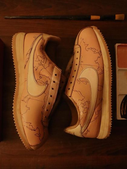 The first step to a masterpiece. This is a pair of Nike Cortez after being dyed in coffee, with the world map base carefully painted on. This clean canvas is ready for the final layers of personalized art.