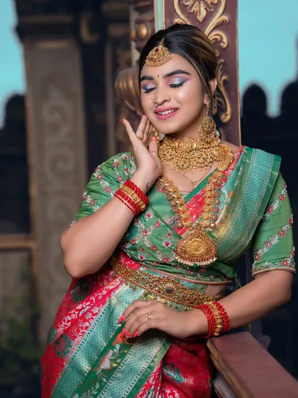 A student portfolio shot featuring a green and red saree. The makeup includes shimmery eyeshadow and a glossy lip.