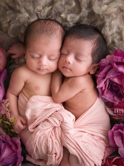 A bed of roses for two sleeping beauties. The rich colors of the flowers provide a stunning contrast to the soft skin of these newborn twins, creating a fine art portrait.