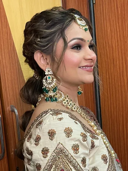 A side profile showing the elegant hairstyle and the stunning emerald jewelry.