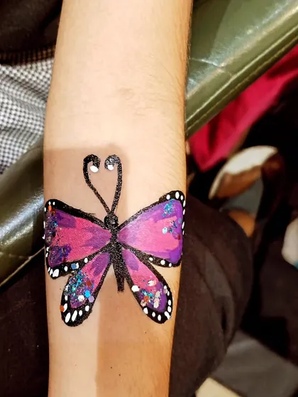This purple butterfly arm painting is another example of a popular and beautiful design, finished with glitter for a sparkling effect.