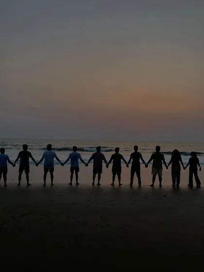 A silhouette of our group holding hands against the sunset on Gokarna beach, a symbol of the friendships we build.