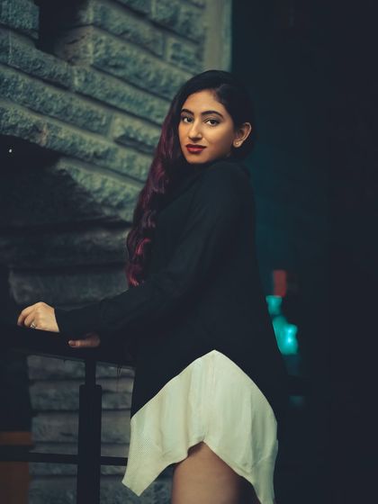 A night portrait using ambient city lights to create a moody and mysterious feel. The dark tones and pop of color in the subject's hair add to the cinematic quality of the shot.