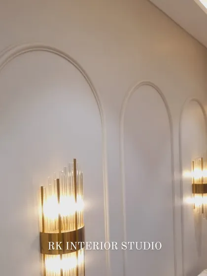 Elegant wall sconces mounted on a wall with arch-shaped moulding. This classic detail adds a touch of sophistication and provides soft, ambient lighting for the bedroom.