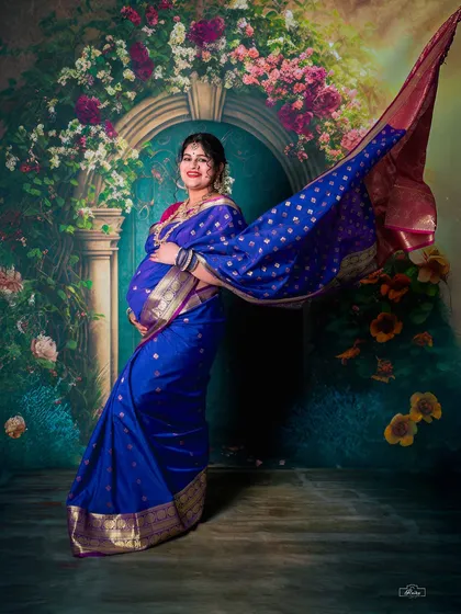 The timeless elegance of a traditional saree maternity shoot. This studio portrait uses dramatic posing and lighting to highlight the beauty of the mother-to-be and her gorgeous blue silk saree.