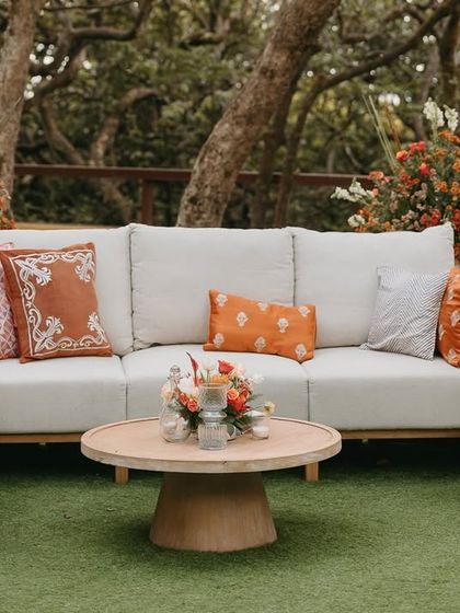 A comfortable and stylish lounge area with natural wood furniture and custom-printed cushions in shades of orange.