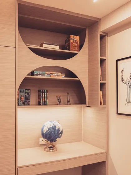 A close-up of the study area integrated into a custom wardrobe unit. The curved shelves create a soft, organic feel, providing a perfect space for books and decor items.
