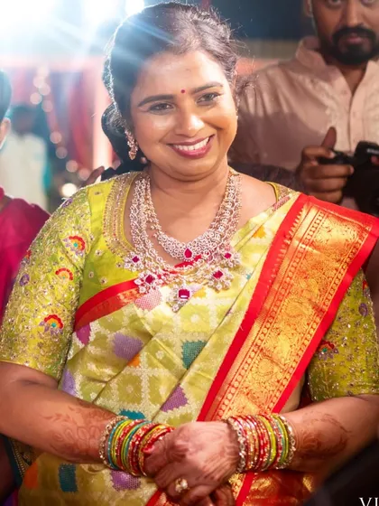 The mother of the bride looking radiant in a lime green saree. Her custom blouse is heavily embroidered with colorful threads, making her stand out.