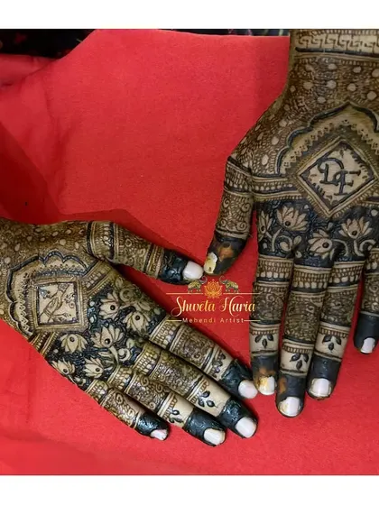 The back of the hands is a canvas for striking artwork. This design uses a dual-tone or 'meenakari' style, with bold, dark-filled lotus patterns that stand out against the intricate linework, creating a high-contrast, memorable look.