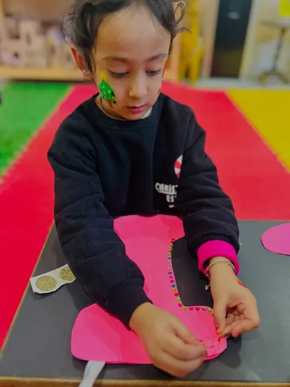 A close-up of a student carefully decorating her stocking craft.