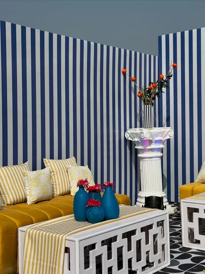 A wide shot of a lounge area from the Uttarayan festival. The decor combines geometric patterns on the floor and furniture with bold stripes on the walls, creating a highly graphic and modern look.