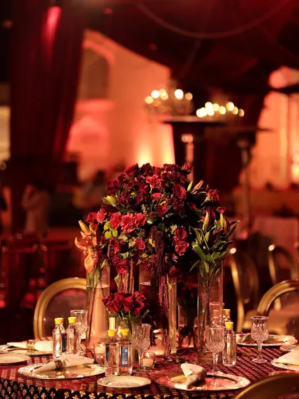 The magic is in the details. A close-up of a tablescape from a sundowner wedding, where deep red florals, crystal glassware, and soft candlelight come together to create a rich, romantic, and intimate dining experience for every guest.