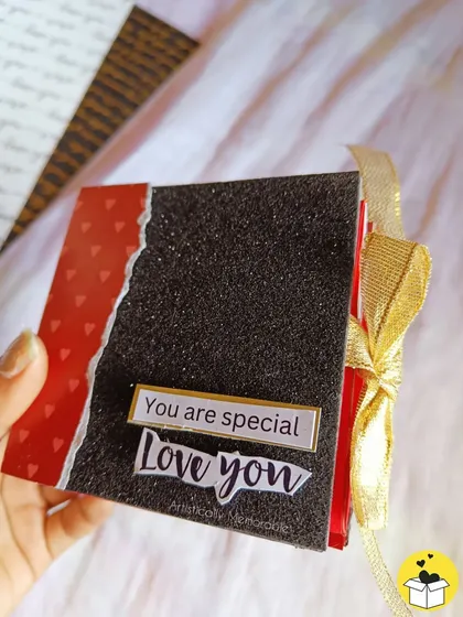Holding the glittery black mini album, tied with a gold ribbon. It's a very chic and cute gift.