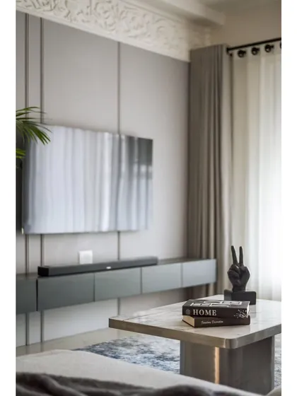 The TV wall in the living room features a muted grey tone with an intricate ornamental design patch at the top. The design is eye-catching without dominating the rest of the space.
