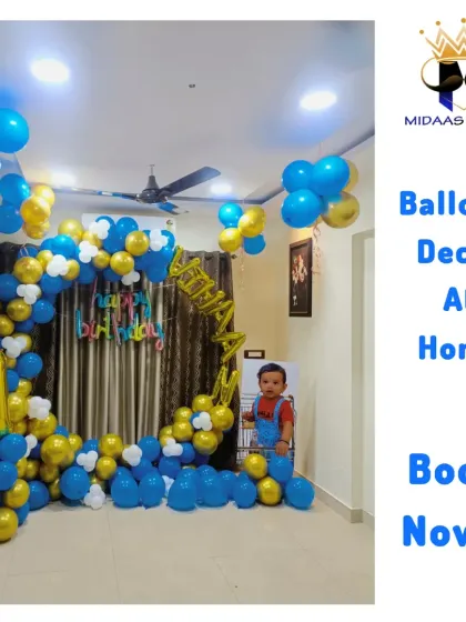 I bring the party right to your doorstep. This is a complete first birthday decoration at home, featuring a circular balloon arch in blue, gold, and white, with foil balloons for the name and number '1'. It's a perfect way to celebrate milestones without booking a hall.