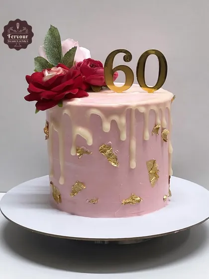 A beautiful pink drip cake for a 60th birthday. This butterscotch cake is decorated with gold leaf and fresh red roses for a classic and elegant look.