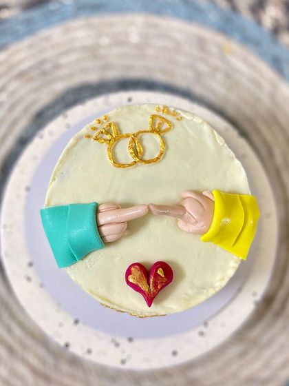 A top-down view of our cute engagement cake, showing the rings and proposal gesture.