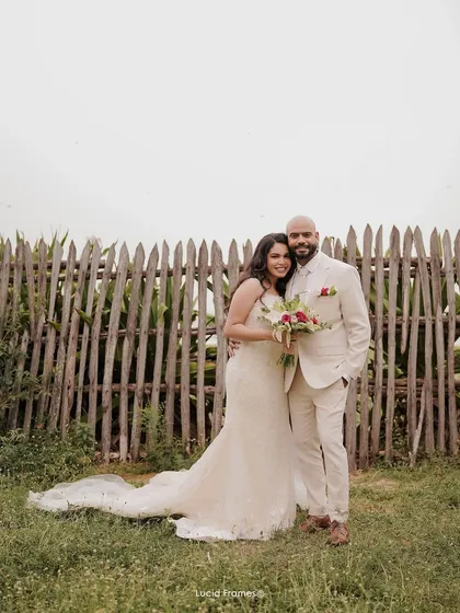 A classic wedding portrait of the bride and groom against a rustic wooden fence, a timeless image from their special day.