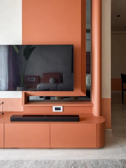 A detail shot of the TV unit, showing the reflection of the living room in the screen. The design is both functional and aesthetically pleasing.
