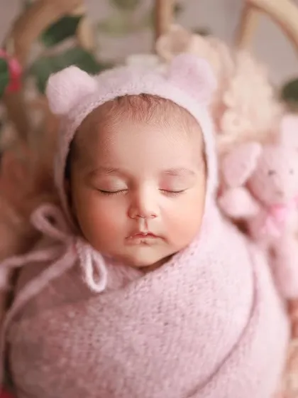The little bear ears on this pink bonnet are just too cute. This close-up shot captures the baby's perfect, serene face.