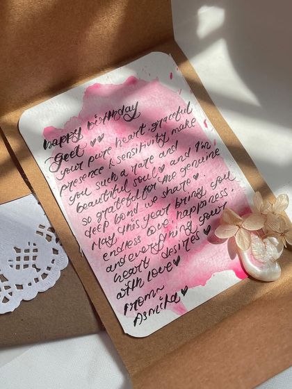 A peek inside a birthday gift combo. This features a heartfelt, hand-lettered card with a pink watercolor background and a delicate wax seal with dried flowers.
