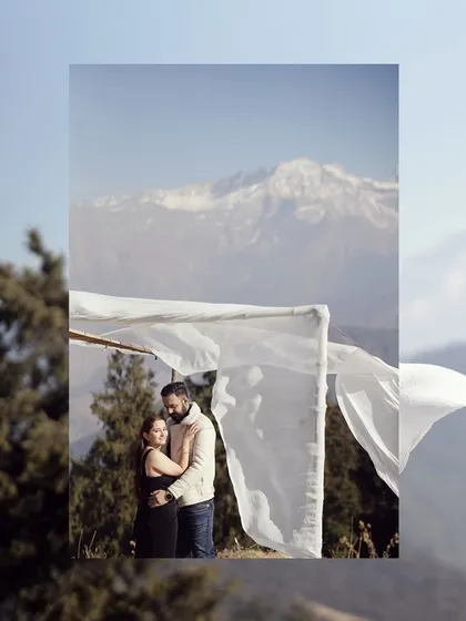 A beautiful portrait of a couple framed by a simple white arch against the stunning backdrop of snow-capped mountains, blending simplicity with grandeur.