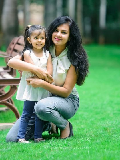 A mother and daughter share a hug in a beautiful green park. This photo captures a natural and loving interaction, perfect for a relaxed family portrait session.