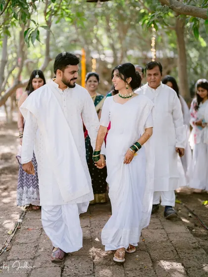 Walking together in serene white. The couple and their families, all dressed in white, create a beautiful, unified picture at this Buddhist wedding.