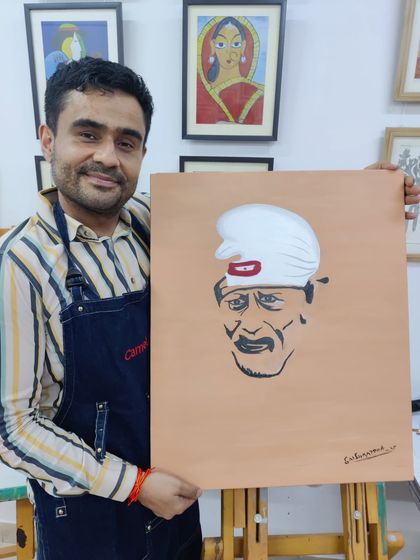 An adult student is captured through the process of painting a portrait of Sai Baba, showing concentration and devotion in his work.