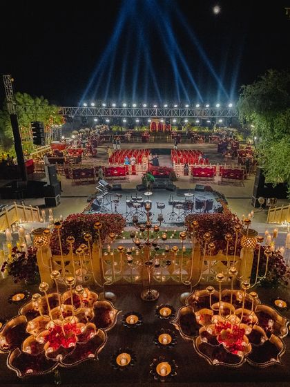 An aerial view of a grand sangeet at Suryagarh. The layout was designed for a massive celebration, with a large stage for performances, tiered seating for guests, and hundreds of candles creating a warm, shimmering glow across the entire venue.