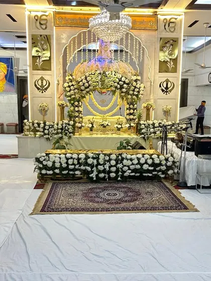 We offer serene and respectful flower arrangements for religious venues. This is a Gurudwara hall we decorated for a Prakash Purab ceremony, using elegant white flowers to adorn the Palki Sahib, creating a peaceful and divine ambiance.
