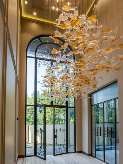 The entrance of our Sultanpur farmhouse sets a tone of neo-classical elegance. The custom-designed fish chandelier is a floating sculpture in the double-height foyer, welcoming you into a space where every detail is a piece of art.