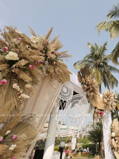Another angle of the bohemian-style arch, showing the lush arrangement of pampas grass and florals against the clear blue sky.