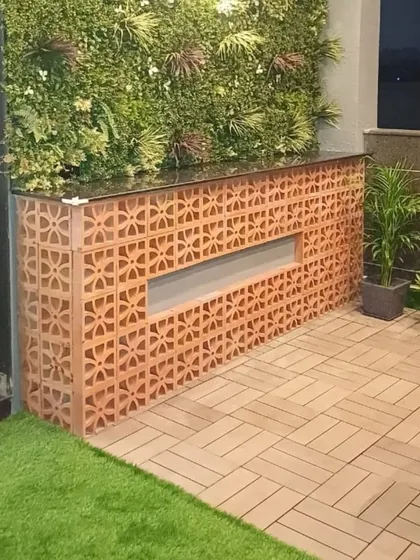 This custom-built bar counter, made with terracotta jali blocks, adds an earthy and traditional touch to a modern terrace. It's paired with a vertical garden and interlocking deck tiles.