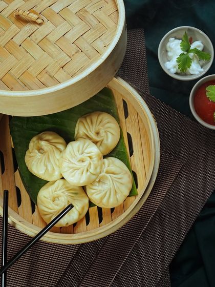Steamed momos beautifully arranged in a traditional bamboo steamer. The composition is authentic and appetizing.