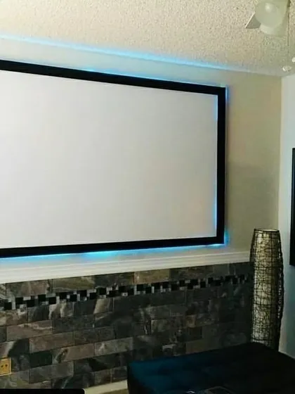 Here, we integrated a projection screen into a living area with distinctive decor. The screen is mounted above a custom stone-tile wall feature, with subtle backlighting to enhance the viewing experience. This approach ensures the technology feels like a natural part of the home's design.