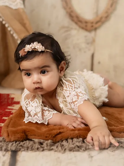 A close-up of the baby in a lacy outfit, showing off her beautiful eyes.