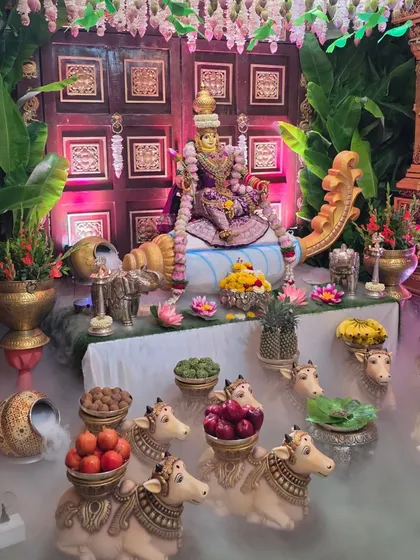 A close-up of my signature Lakshmi doll centerpiece, designed to bring blessings and prosperity. This setup features the goddess seated against a traditional carved wooden door, surrounded by offerings on cow props and an ethereal dry ice fog effect.