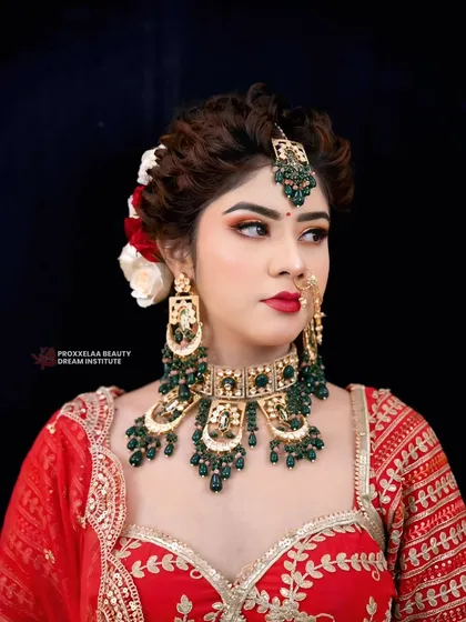 A powerful bridal portrait. The combination of a bold red lip, sharp contour, and emerald green jewelry creates a look of undeniable confidence.